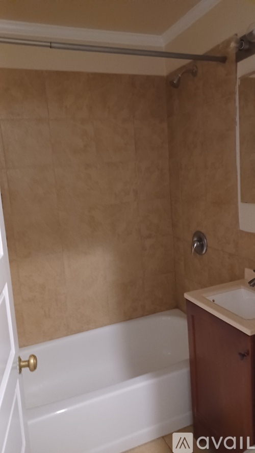 A bathroom with beige walls and a white bathtub.