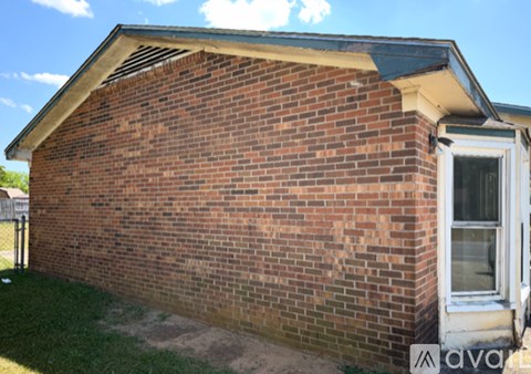 A small red brick house with a white door and a window.
