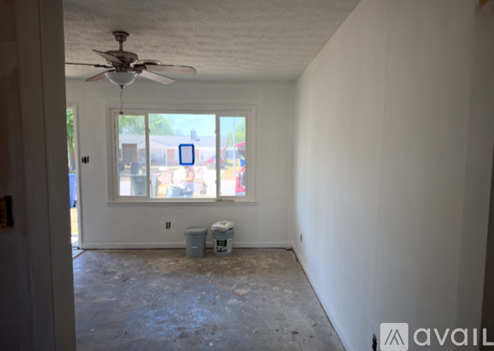 A room with a ceiling fan and a window showing an outdoor scene.