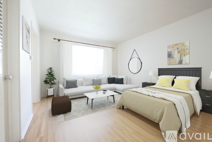 A bedroom with a bed, couch, and a small tree.