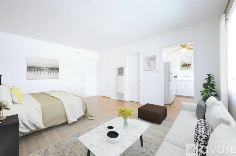 A living room with a white couch, a coffee table, and a bed with a green and beige comforter.