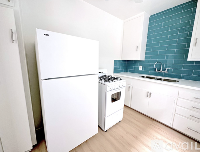 A white refrigerator stands next to a white stove in a kitchen.