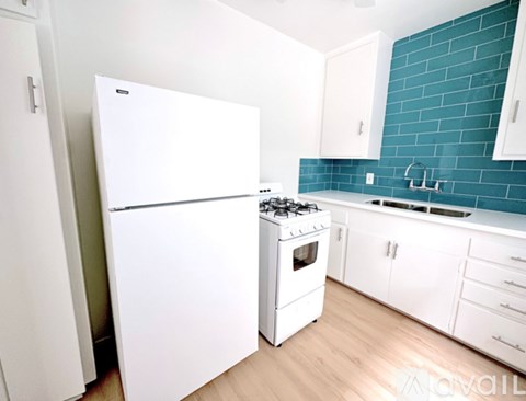 A white refrigerator stands next to a white stove in a kitchen.