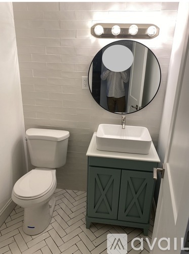 A bathroom with a toilet, sink and mirror.