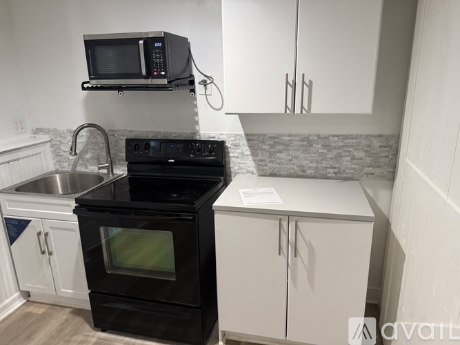 A kitchen with a black stove top oven and a black microwave above it.