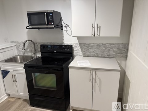 A kitchen with a black stove top oven and a black microwave above it.
