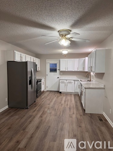 A kitchen with a black fridge and white cabinets.