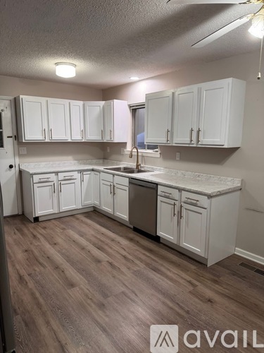 A kitchen with white cabinets and a wooden floor.