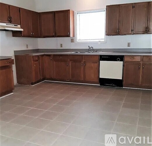 A kitchen with brown cabinets and a white dishwasher.