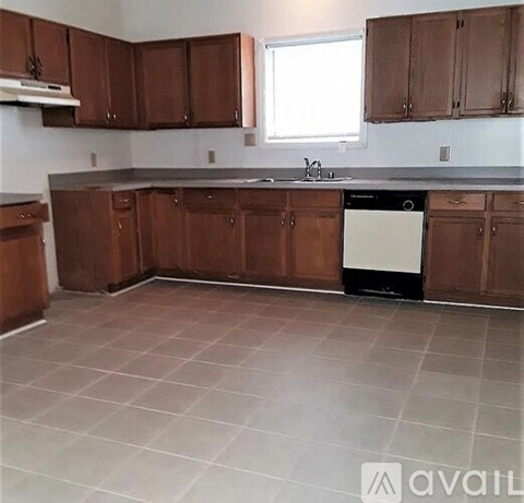 A kitchen with brown cabinets and a white dishwasher.