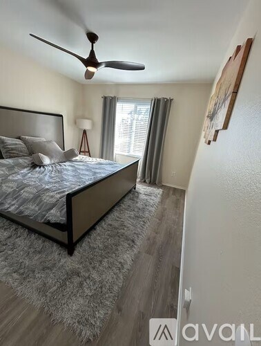 A bedroom with a bed, a ceiling fan, and a rug.