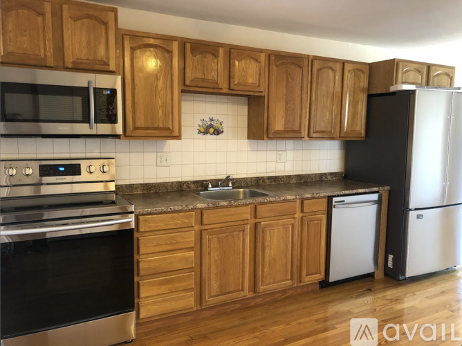 A kitchen with wooden cabinets and a black fridge.