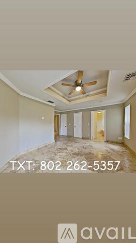 A spacious room with wood flooring and a ceiling fan.