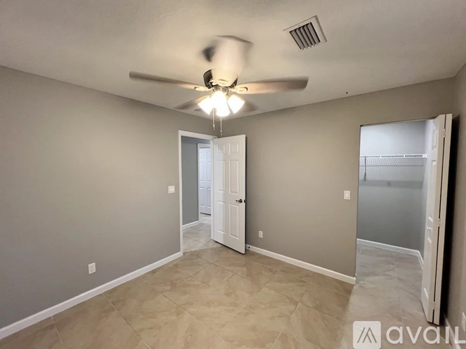 A room with a ceiling fan and a door leading to a balcony.
