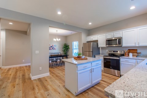 A kitchen with white cabinets and a wooden floor.