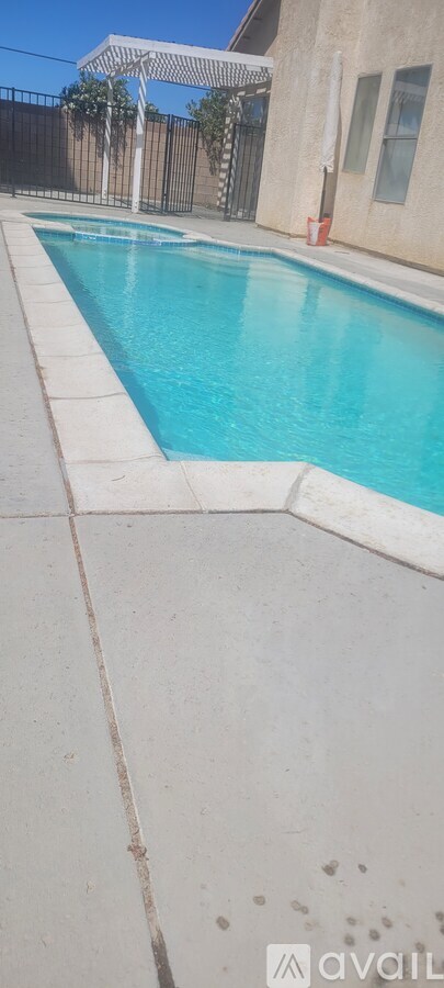 A pool with a white fence and a white umbrella.