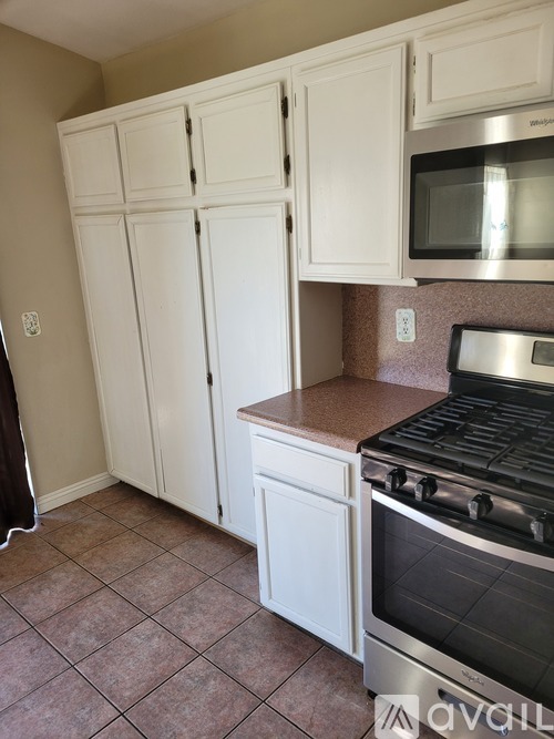 A kitchen with white cabinets and a stainless steel oven.