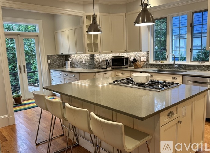 A kitchen with a large island and white chairs.