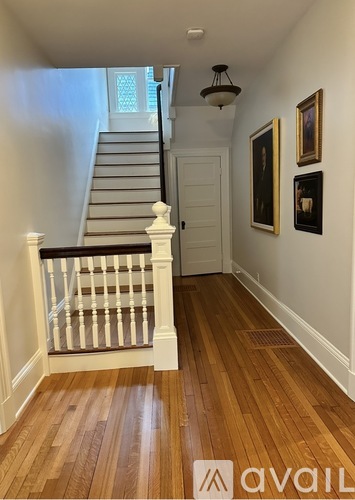 A hallway with a staircase and pictures on the wall.