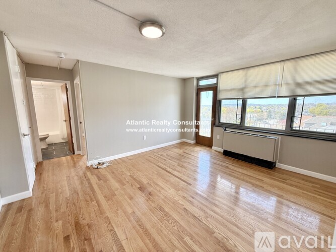 A room with wooden flooring and a large window with blinds.