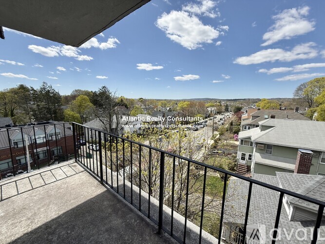 A balcony overlooks a residential area with houses and trees.