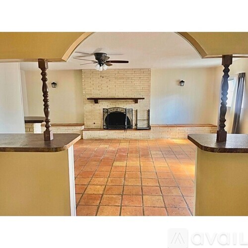 A living room with a fireplace and a ceiling fan.