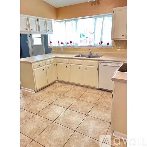 A kitchen with beige cabinets and a tiled floor.