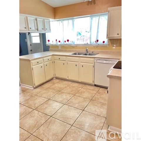 A kitchen with beige cabinets and a tiled floor.