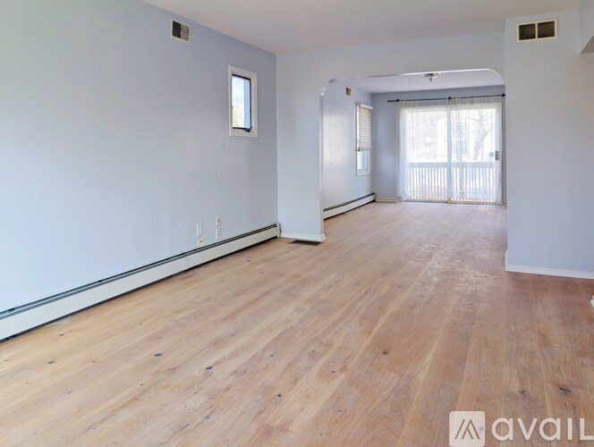 A spacious room with wooden flooring and white walls.