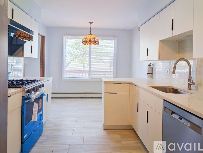 A kitchen with a blue dishwasher and white cabinets.