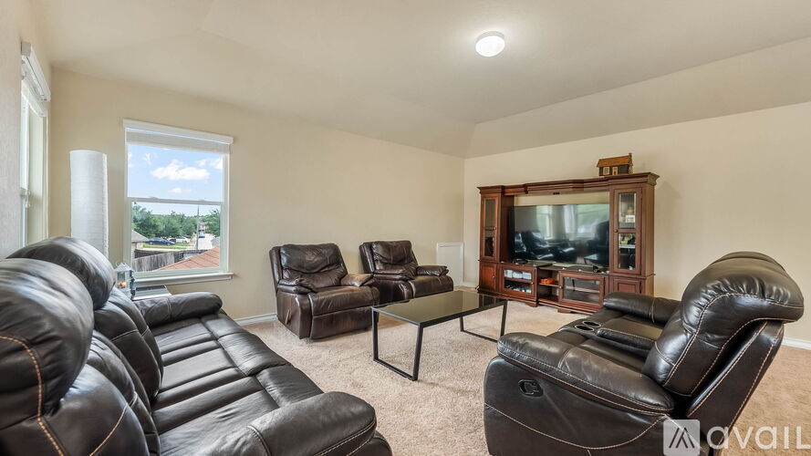 A living room with brown leather furniture and a flat screen TV.