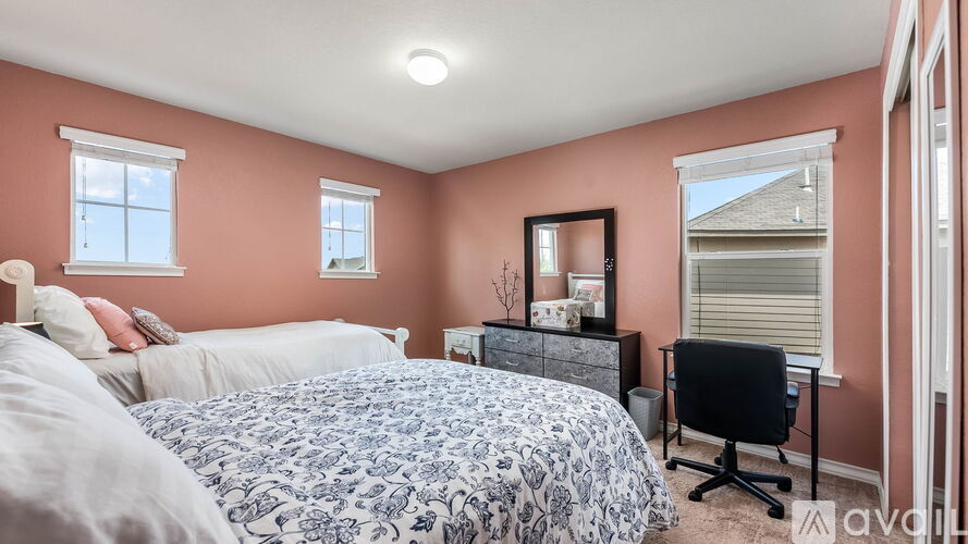 A bedroom with a large bed and a desk with a chair.