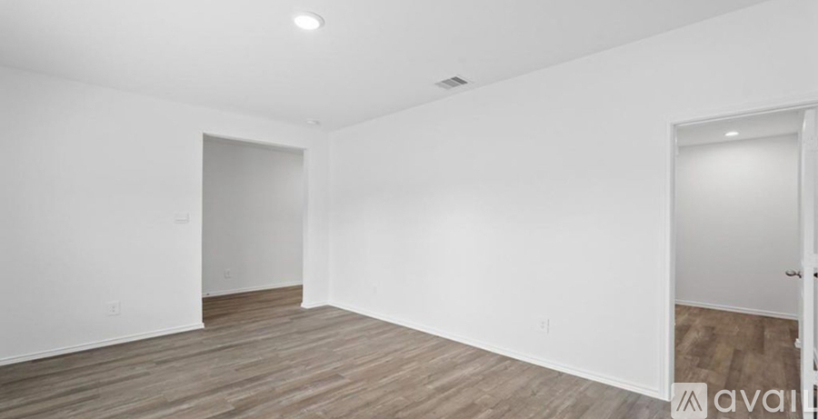 A room with wooden flooring and white walls.