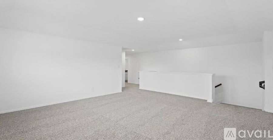 A spacious empty room with carpeted floor and white walls.
