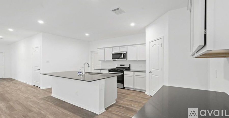 A modern kitchen with white cabinets and a black countertop.