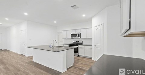 A modern kitchen with white cabinets and a black countertop.