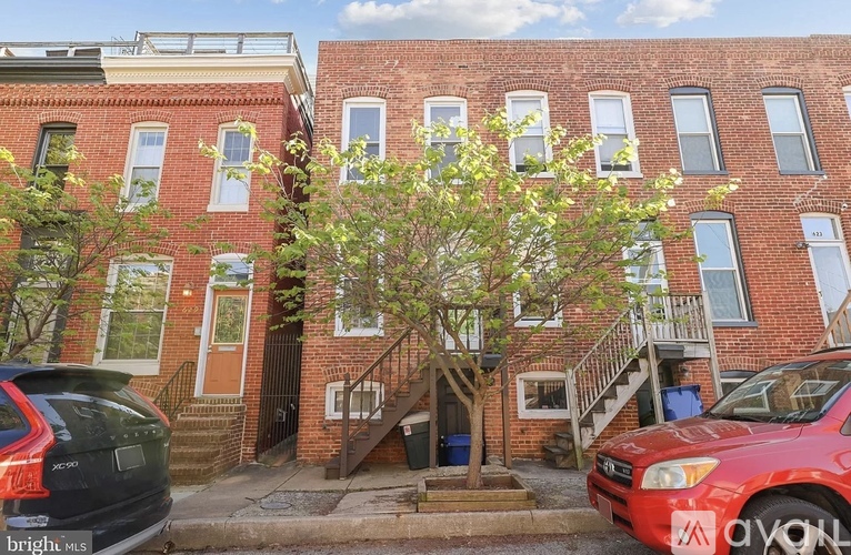 A red car is parked in front of a brick building.