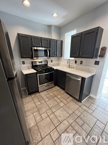 A kitchen with black cabinets and stainless steel appliances.