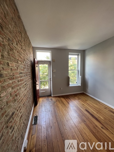 A room with wooden floors and a brick wall.
