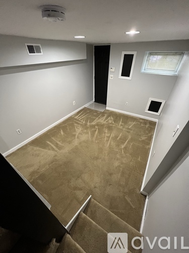 A room with a carpeted floor and a staircase leading to another room.