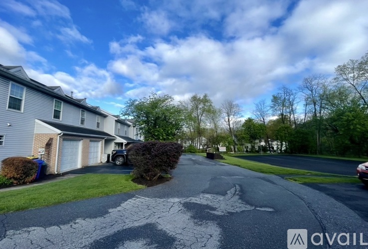 A residential street with houses on both sides and a car parked on the right.