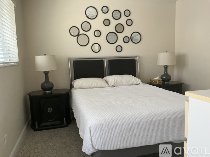 A bedroom with a bed, two nightstands, and a wall decoration.
