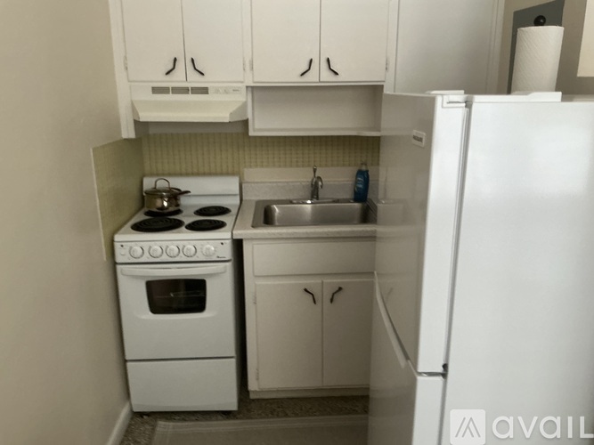 A small white kitchen with a stove, sink, and refrigerator.