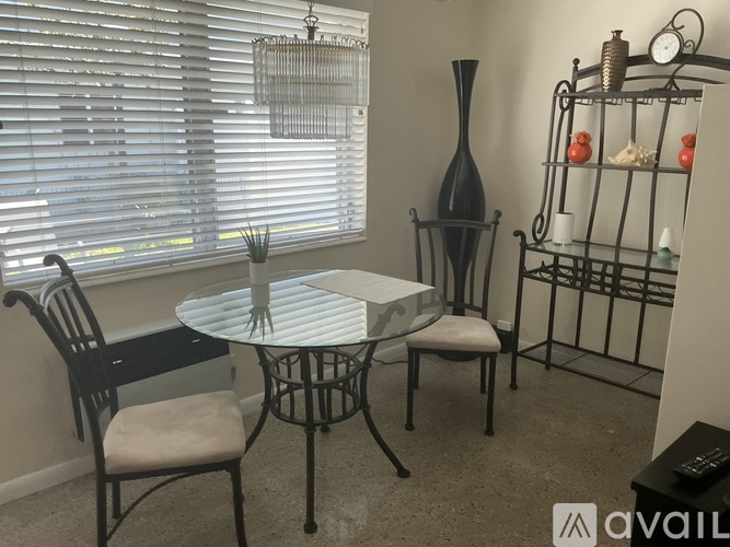 A table with chairs and a shelf with decorative items in a room.