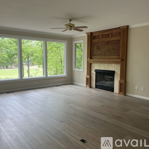 A spacious living room with a fireplace and a ceiling fan.