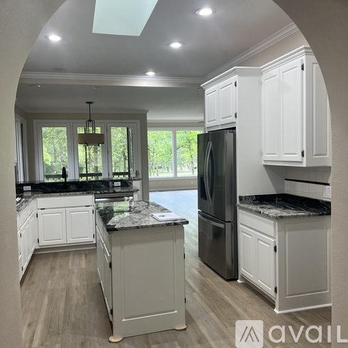 A kitchen with white cabinets and a black refrigerator.