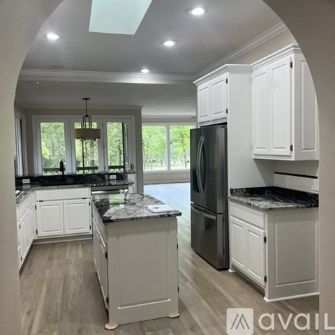 A kitchen with white cabinets and a black refrigerator.