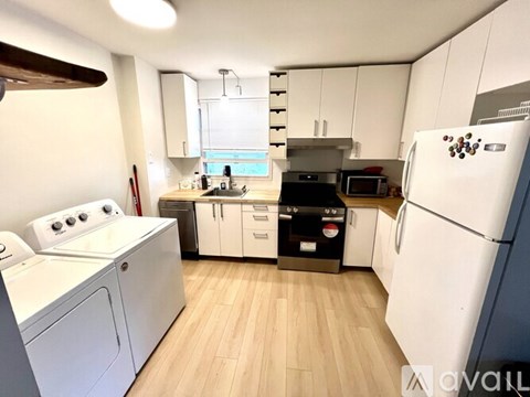 A kitchen with white appliances and wooden floors.