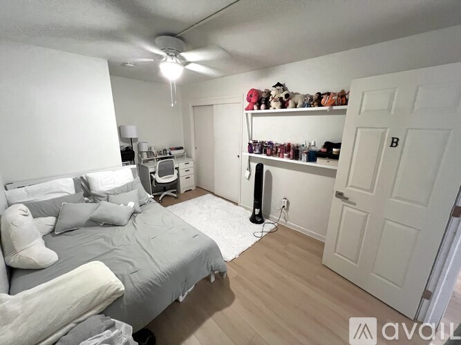 A bedroom with a bed, a fan, and a closet.