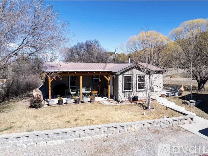 A house with a covered patio and a stone wall in front.